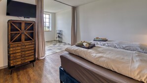 Een slaapkamer met een bed, een houten kast, een televisie en een raam.