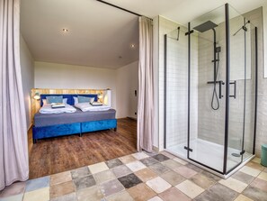 Une chambre à coucher moderne avec un grand lit, une douche en verre et un plancher en bois.