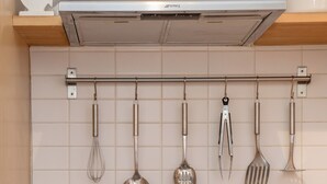 A kitchen with a stainless steel range hood, a hanging utensil rack, and a built-in oven. - Grassmarket Modern Two Bedroom Flat  (Edinburgh)