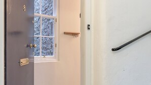 A door leading to a room with a window, a doormat with "WELCOME" text, and a staircase. - Grassmarket Modern Two Bedroom Flat  (Edinburgh)