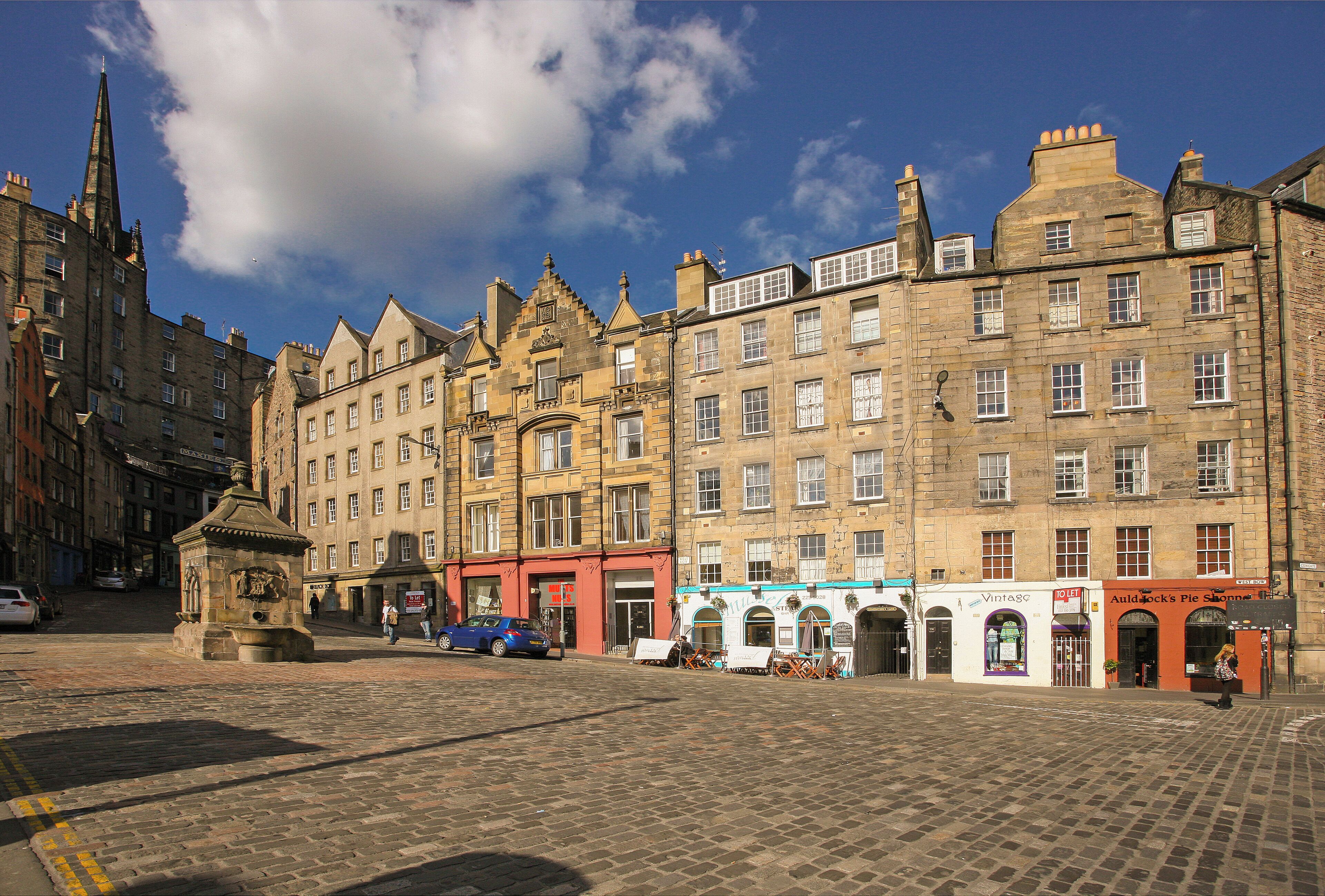 A historic street with traditional architecture, cobblestone pavement, and a mix of commercial and residential buildings.