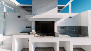 Una cocina exterior moderna con una parrilla empotrada, un fregadero y un salpicadero azulejado.