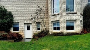 A two-story house with a brick exterior, a front door, and two windows on the upper floor. - New modern vacation apartment by the forest. (Bückeburg)