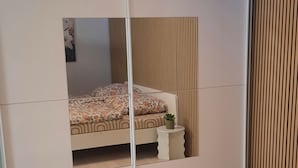 A bedroom with a bed, a wardrobe, and a mirror. - New modern vacation apartment by the forest. (Bückeburg)