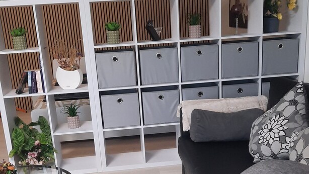 A modern living room with a sectional sofa, a glass coffee table, and a white storage unit with multiple compartments. - New modern vacation apartment by the forest. (Bückeburg)