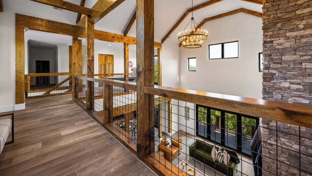 Un loft spacieux avec des poutres apparentes, un mur en pierre décoratif et une vue sur l’extérieur.