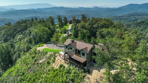 Une maison entourée d’une forêt dense, offrant une vue dégagée sur les montagnes lointaines.