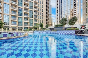 A swimming pool with blue checkered tiles, surrounded by high-rise residential buildings with balconies. - FIRST CLASS | 3BR | Prime Downtown City Lights (Downtown)