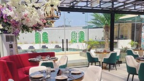 Un restaurante con mesas redondas, sillas color turquesa y un sofá rojo.