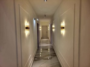 A hallway with marble flooring, wall-mounted light fixtures, and a door at the end. - Luxury absolute privacy with perfectly situated in the prestigious Banana Island (Lagos)