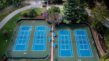 Vue aérienne d’un complexe de courts de tennis comprenant plusieurs terrains, entouré d’arbres et d’un quartier résidentiel.