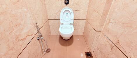 Un baño con inodoro blanco, ducha y desagüe.