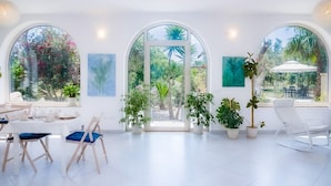 A bright, spacious room with large windows, a dining area with chairs and a table, and several potted plants. - Casa Giada nel cuore del Salento (Gallipoli)
