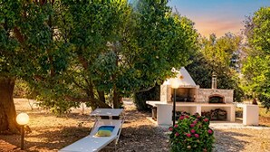 An outdoor seating area with a stone fireplace, surrounded by trees and a gravel path. - Casa Giada nel cuore del Salento (Gallipoli)