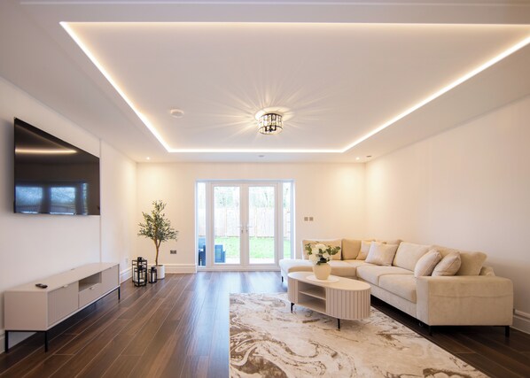 A modern living room with a sofa, coffee table, and TV. - Beautiful 4 Bed House - Close to Windsor Castle! (Windsor)