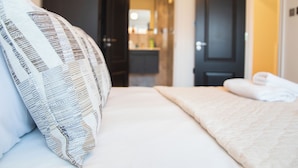 A hotel room with a bed, a pillow, a blanket, and a door leading to a bathroom. - Beautiful 4 Bed House - Close to Windsor Castle! (Windsor)