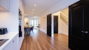 A modern kitchen with a dining area, wooden flooring, and a staircase leading to another level. - Beautiful 4 Bed House - Close to Windsor Castle! (Windsor)