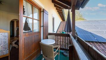 Ein Balkon mit Tisch und Stühlen, eine Holztür und Solaranlagen auf dem Dach.