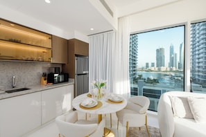 A modern kitchen with a dining area, a refrigerator, and a view of a cityscape.
