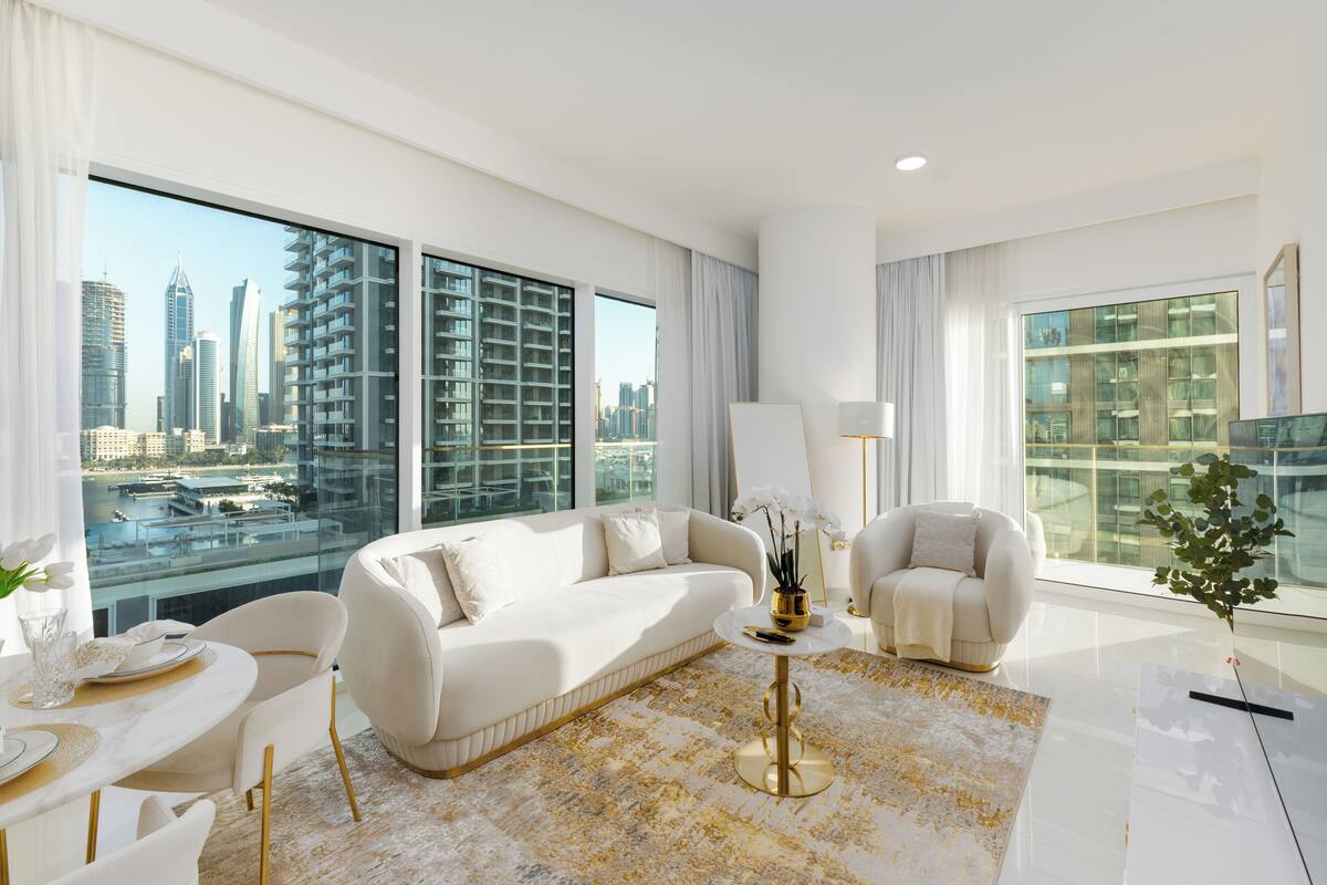 A modern living room with a sofa, armchairs, a coffee table, and a dining area with a table set for two.