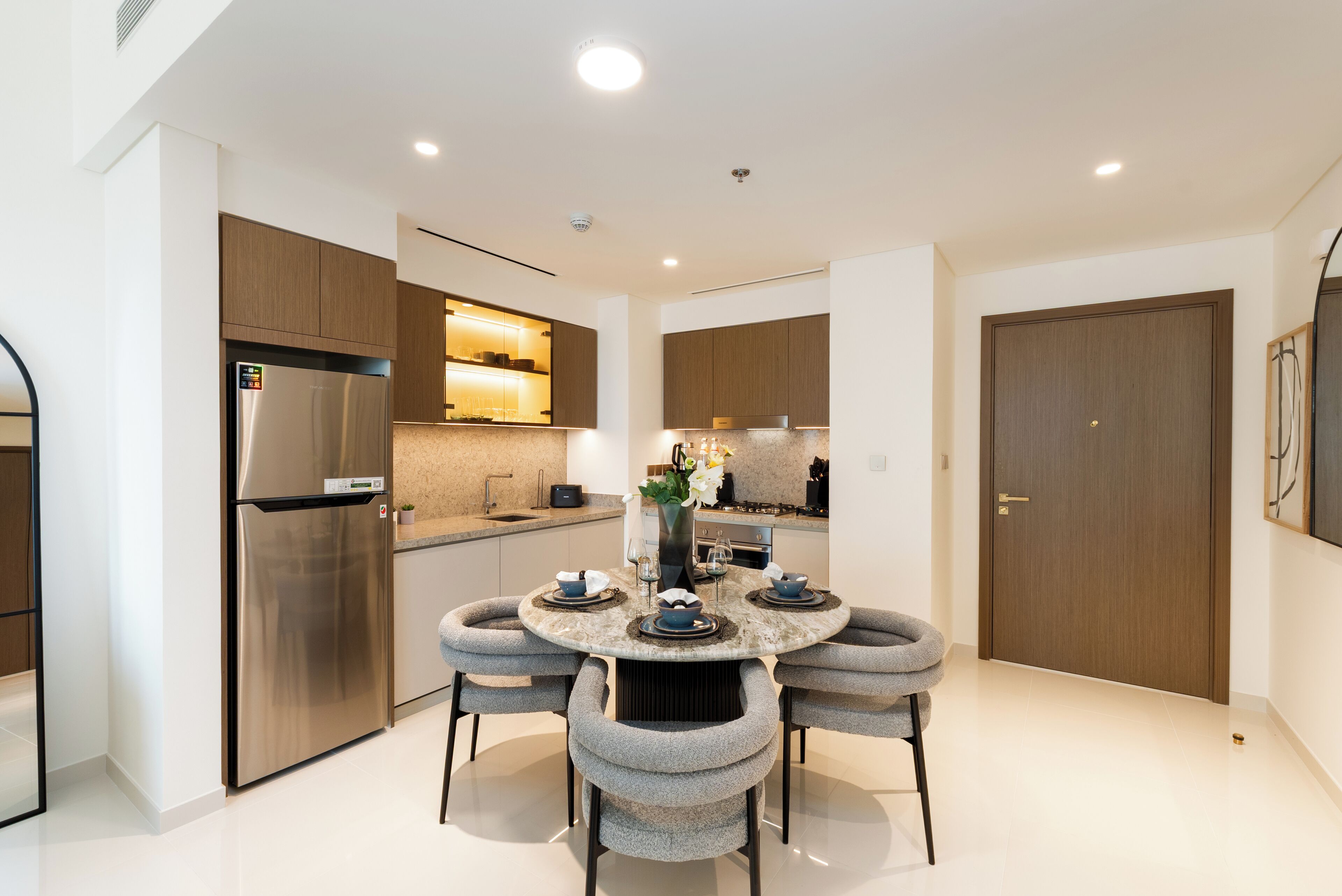 A modern kitchen with a central island, stainless steel appliances, and a dining area with a round table and chairs.