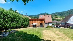 A rural setting with a wooden barn, a house with a red roof, and a clear blue sky.
