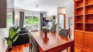 Un salon moderne avec une table à manger en bois, des canapés gris et une grande fenêtre avec des rideaux.