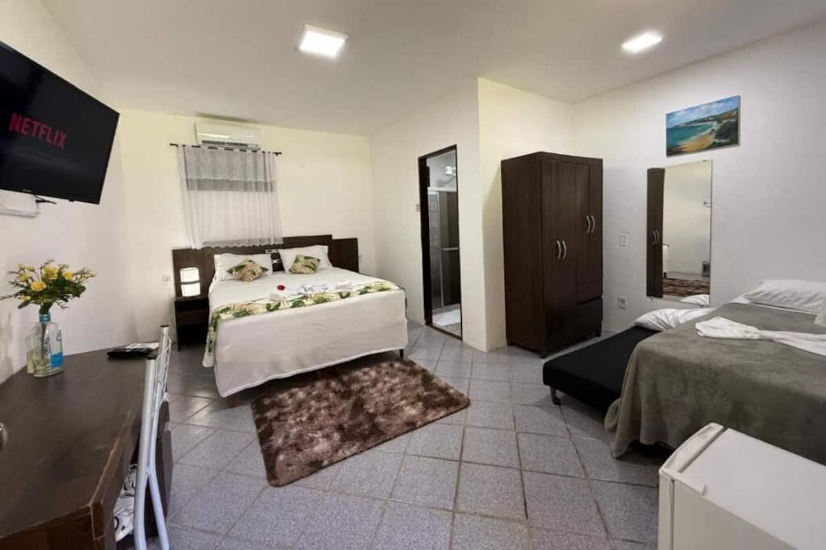 A hotel room with a bed, a desk, a wardrobe, and a TV.