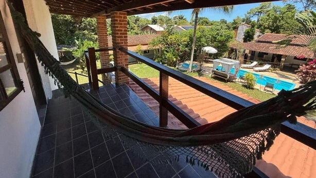 A hammock on a balcony overlooking a pool and lush greenery. - Bella vida274 (Porto Seguro)