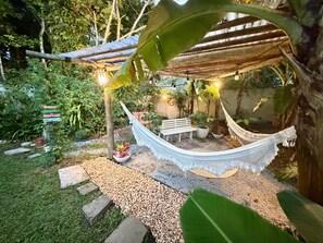A hammock under a wooden pergola in a garden with a gravel path and potted plants. - Bella vida274 (Porto Seguro)