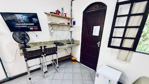 A compact kitchen with a gas stove, a fan, a refrigerator, and a TV mounted on the wall. - Bella vida274 (Porto Seguro)