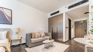 A modern hotel room with a sofa, a small side table, a coffee table, and a dining area with a table and chairs. - Tranquil Studio with City View, O10 Building (Dubai)