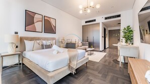 A modern bedroom with a large bed, bedside tables, a desk, and a seating area. - Tranquil Studio with City View, O10 Building (Dubai)
