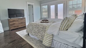 Quarto com cama, penteadeira, televisão e ventoinha no teto.
