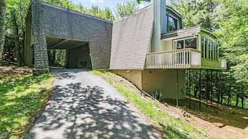Een modern gebouw met een overdekt buitengebied, een pad dat er naartoe leidt, en bebossing op de achtergrond.