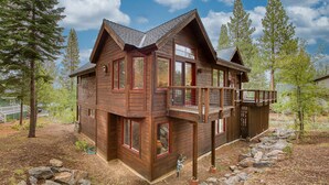 A wooden cabin with a balcony, surrounded by trees and a stone pathway. - Easy Living at Northstar by Tahoe Getaways - 4BR Pet Friendly w/ Ski Shuttle & HOA (Truckee)