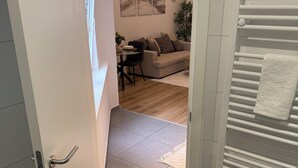 A doorway leading to a living area with a sofa, a coffee table, and a plant. - Ground Serenity (Saint-Gilles)