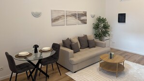 A modern living room with a sofa, a glass dining table, and a coffee table. - Ground Serenity (Saint-Gilles)