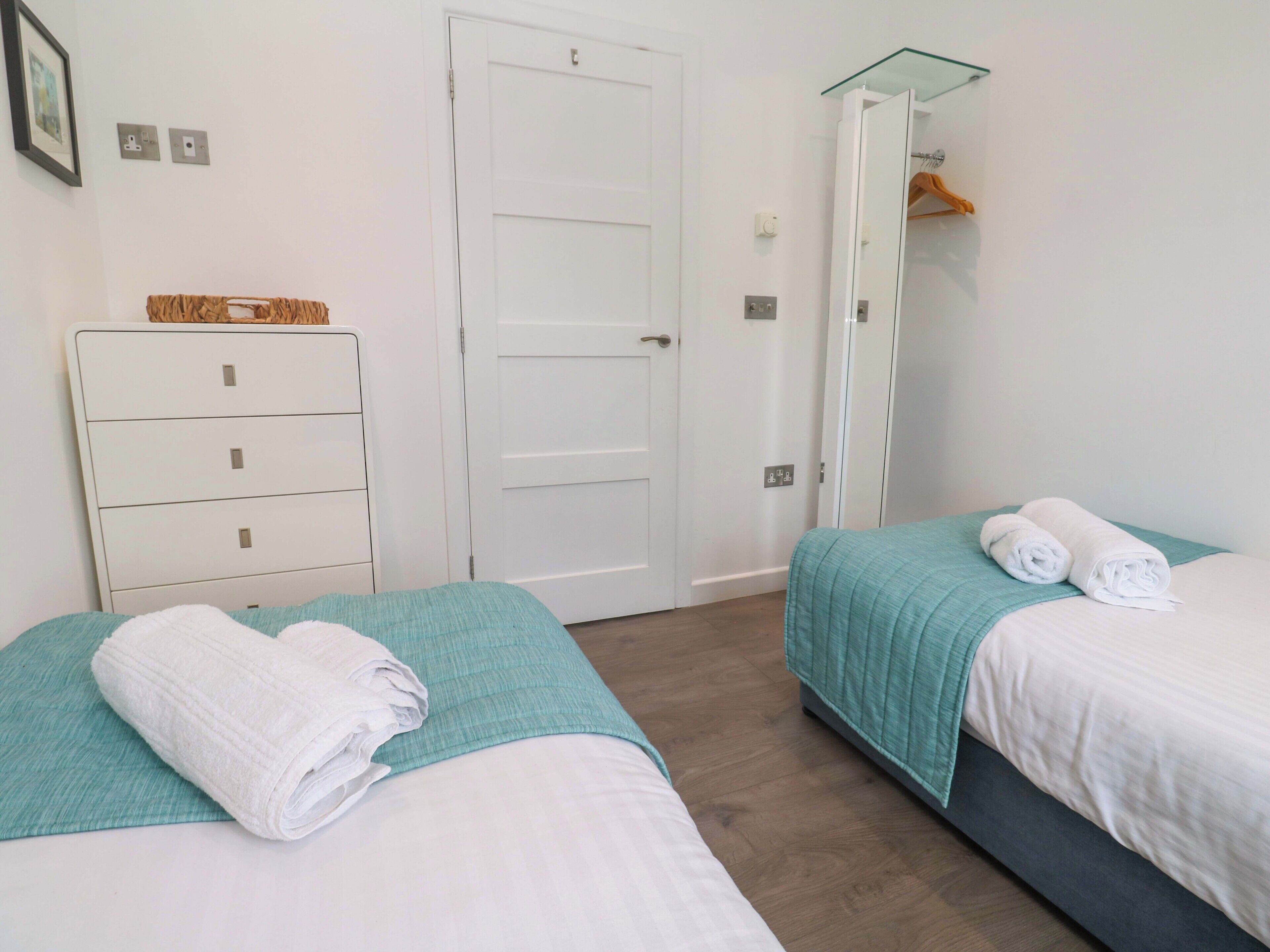 Een hotelkamer met twee bedden, een kast, een spiegel en een glazen plank.