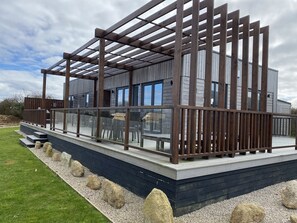 Un edificio moderno con terraza de madera y ventanas amplias.