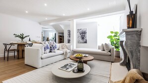 A modern living room with a white sofa, a round coffee table, and a fireplace. - Winelands Mountain View Oasis - 3 Bedroom House, Gym, Pool, Cinema, Lounge, BBQ (Franschhoek)
