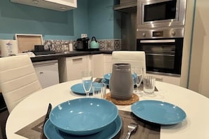 A modern kitchen with a dining area set for four. - Quiet studio within the city walls, 150m from the beach (Saint-Malo)