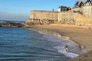 A coastal beach with a historic stone wall and buildings in the background. - Quiet studio within the city walls, 150m from the beach (Saint-Malo)
