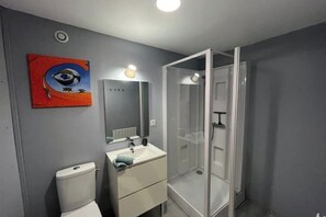 A modern bathroom with a toilet, sink, and glass shower enclosure. - Quiet studio within the city walls, 150m from the beach (Saint-Malo)