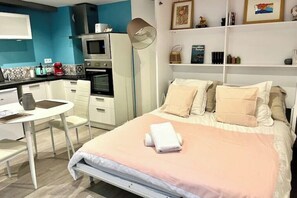 A bedroom with a bed, bedside table, and a small desk with a chair. - Quiet studio within the city walls, 150m from the beach (Saint-Malo)