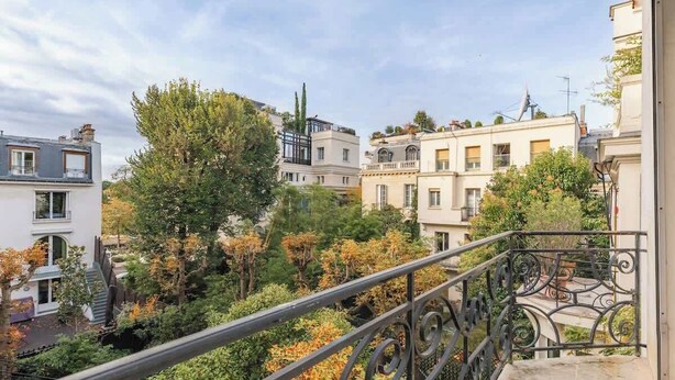 Un quartier résidentiel avec des immeubles, des arbres et une balustrade de balcon.