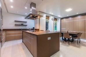 Une cuisine moderne dotée d’un îlot central, de meubles de rangement intégrés et d’un coin repas avec une table et des chaises.