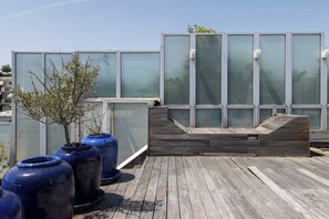 A rooftop terrace with large blue planters, a wooden deck, and a modern building with large windows. - Stunning private hotel with rooftop terrace - Neuilly (Neuilly-sur-Seine)