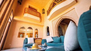 A spacious living area with a teal sofa, a coffee table, and a decorative hat. - Domaine Almaz 2 Villas and 3 Pools (Aghouatim)
