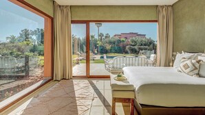 A bedroom with a large window, a bed, a bench, and a view of an outdoor area with a pool and lounge chairs. - Domaine Almaz 2 Villas and 3 Pools (Aghouatim)